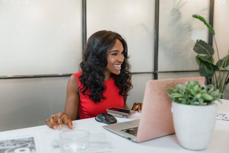 A small business owner smiling while working at a laptop