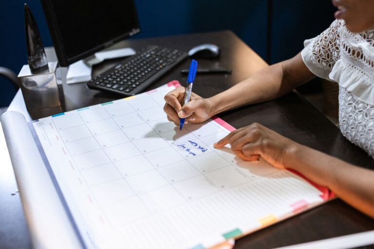 Writing on a desk calendar to plan the month