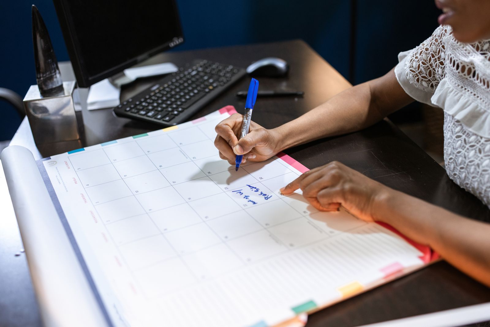 Writing on a desk calendar to plan the month