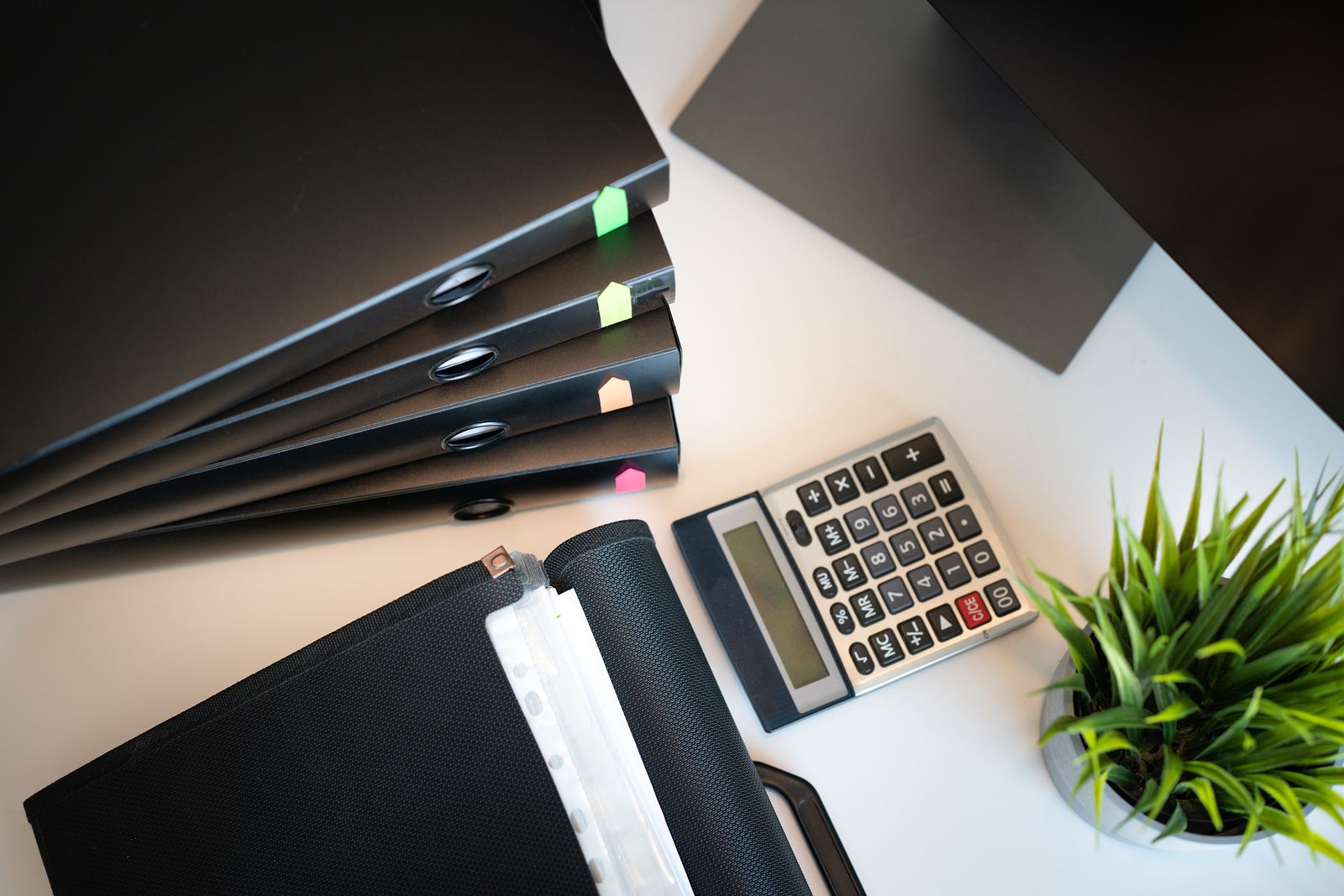Tidy office desk with files, a calculator, and a plant