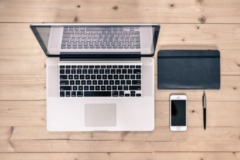 A tidy desk with a laptop, notebook, and phone from above