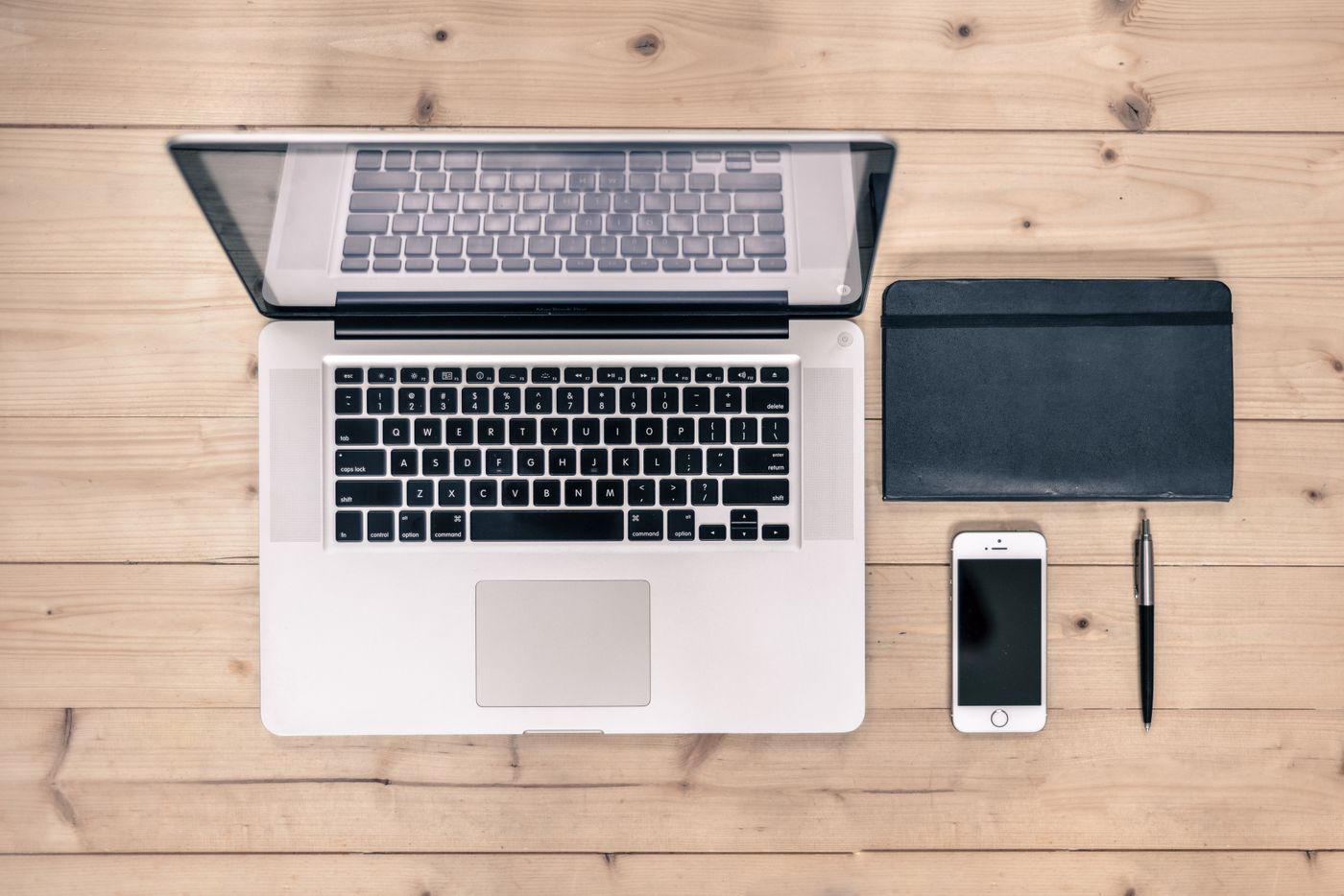 A tidy desk with a laptop, notebook, and phone from above