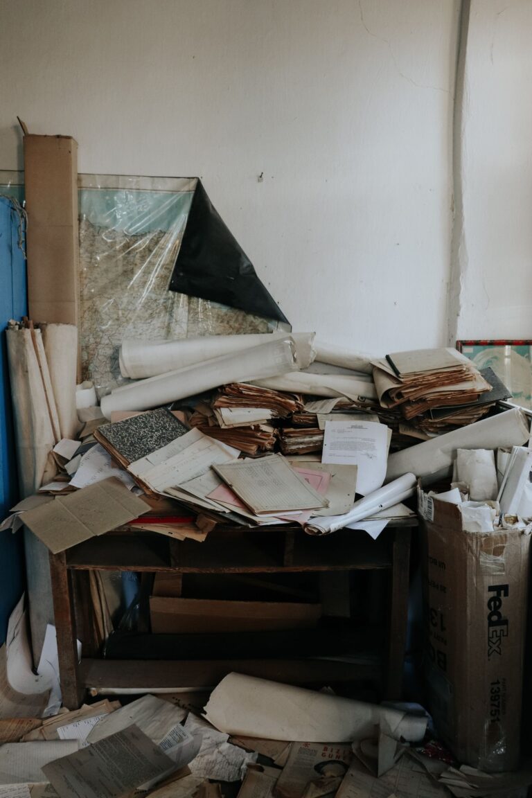 A desk piled with disorganized papers and documents